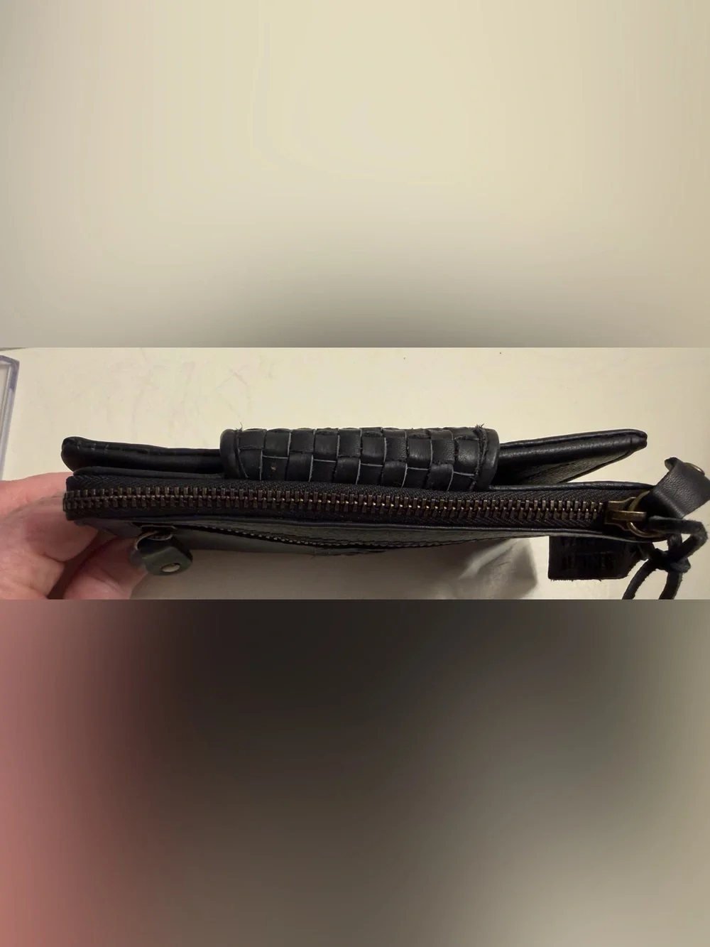 Leather wallet in black with woven flap closure.